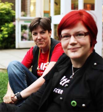 Two people sitting outdoors at BiCon Bisexuality Convention, smiling