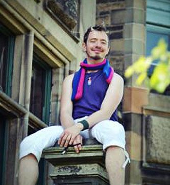 Person at BiCon bisexuality event sitting on top of a pillar, wearing bisexual colours and horns